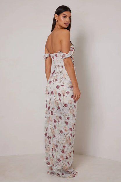 Woman wearing a floral off-shoulder dress against a plain background