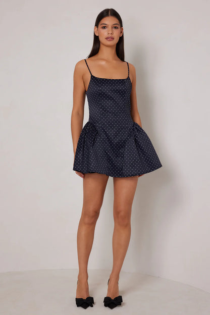 Woman wearing a navy polka dot dress against a white background