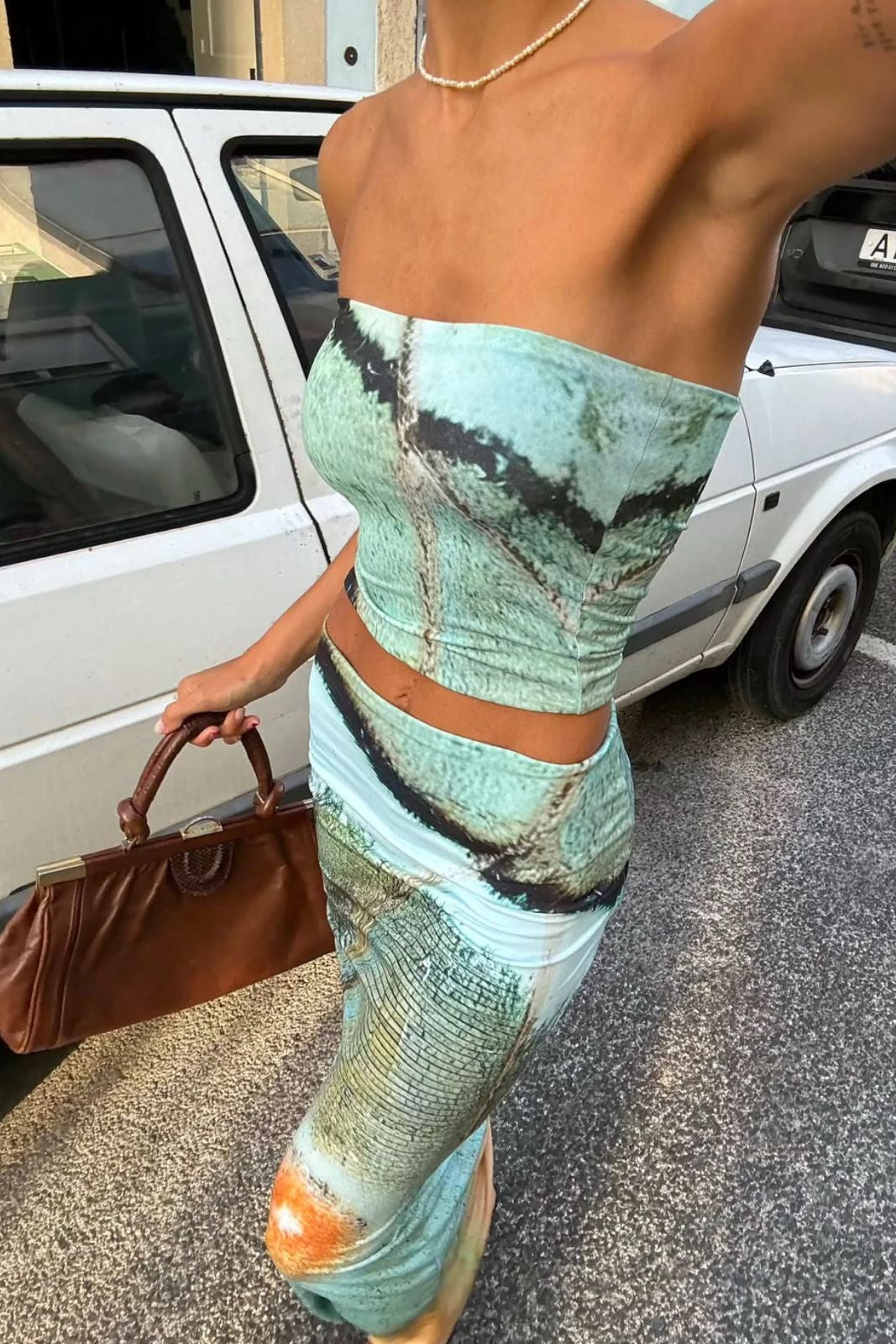 Person wearing a green patterned outfit with a car in the background