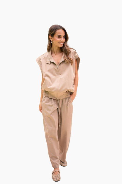 Woman wearing a beige sleeveless top and pants on a white background