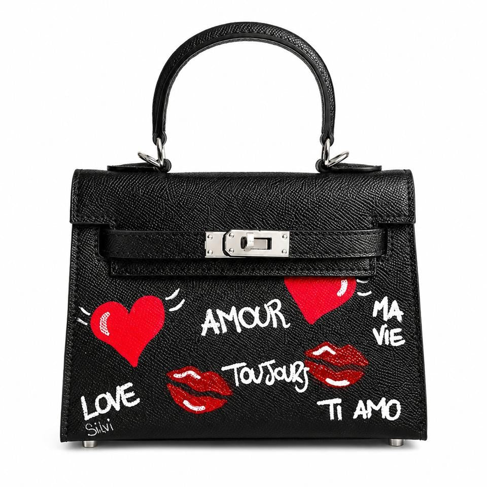 Black handbag with red hearts, white text, and red lips on a white background