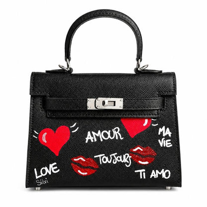 Black handbag with red hearts, white text, and red lips on a white background