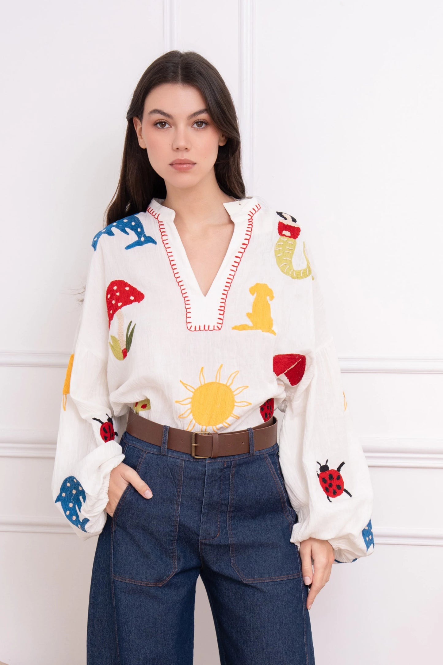 Woman wearing a colorful blouse with cartoon designs against a white background