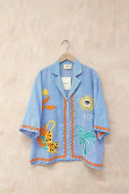 Blue striped shirt with colorful embroidery on a beige background
