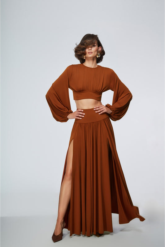 Woman wearing a brown outfit with a long skirt and top on a white background