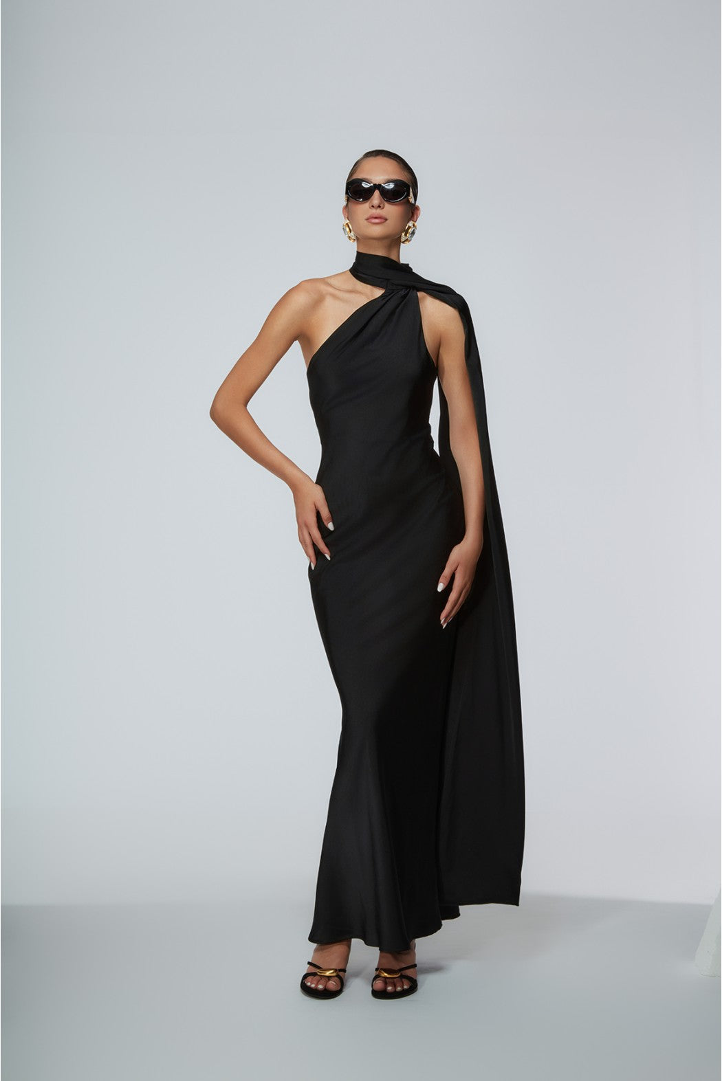 Woman wearing a black one-shoulder dress against a gray background