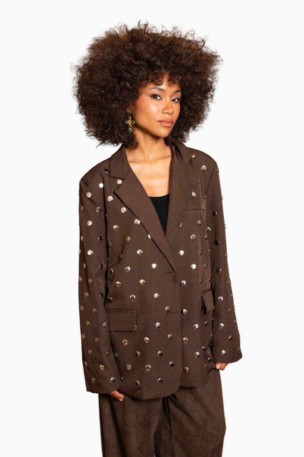 Woman wearing a brown blazer with decorative studs on a white background