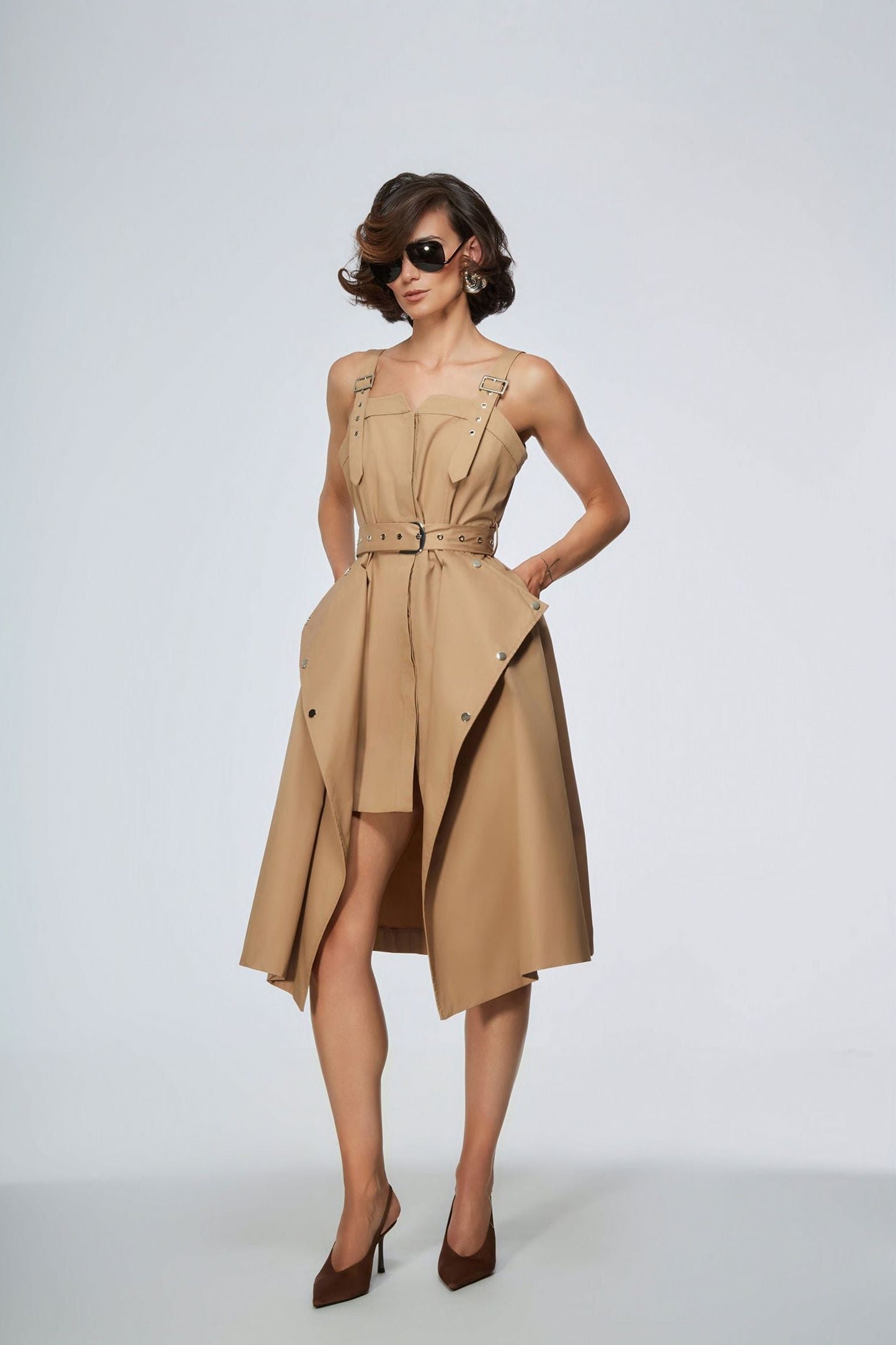 Woman wearing a beige dress with a belt on a light gray background