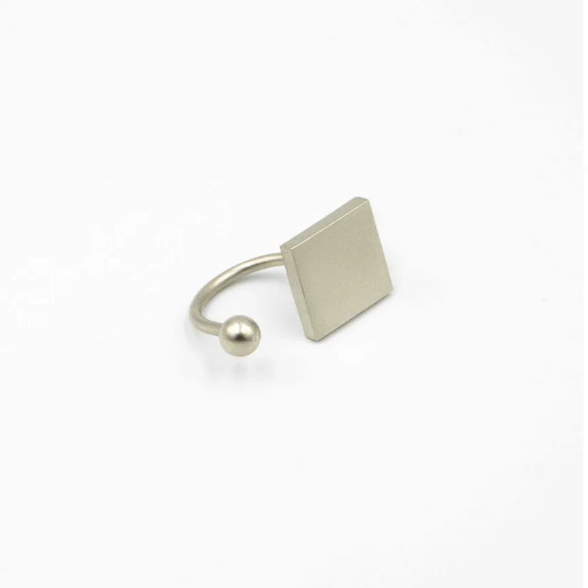 Silver ring with a square pendant and ball detail on a white background