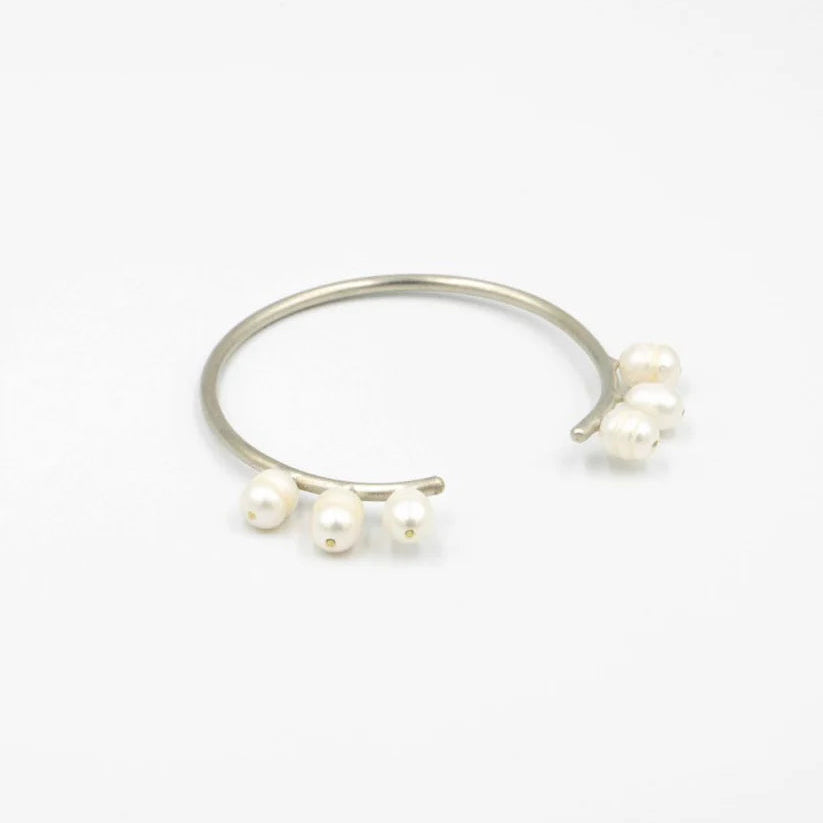 Silver ring with three pearls on a white background