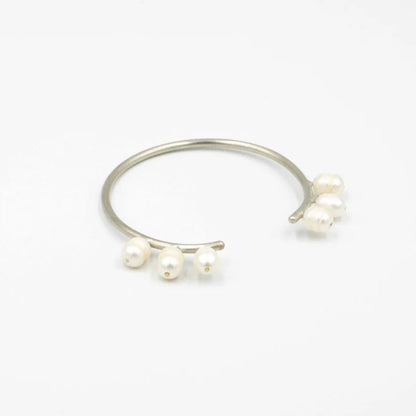 Silver ring with three pearls on a white background
