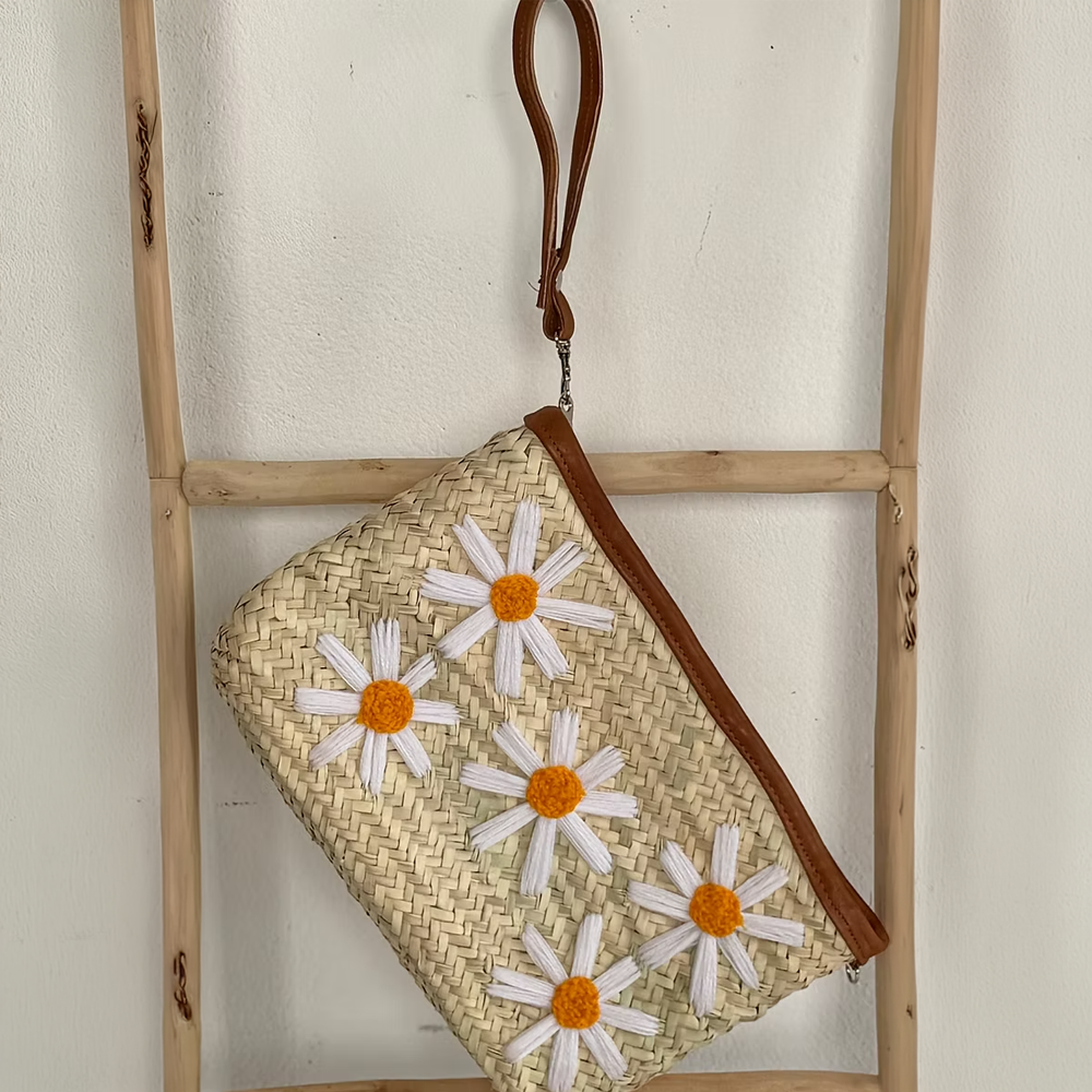 Woven clutch with floral embroidery on a wooden ladder against a white wall