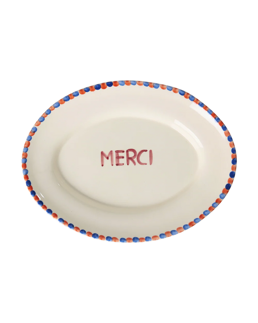 White plate with 'MERCI' text and colorful rim on a white background