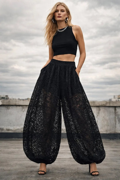 Woman wearing a black outfit with wide-leg pants on a rooftop with a cloudy sky.