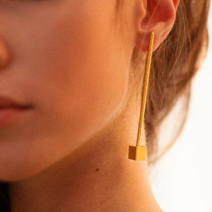 Close-up of a gold earring worn by a person with a blurred background