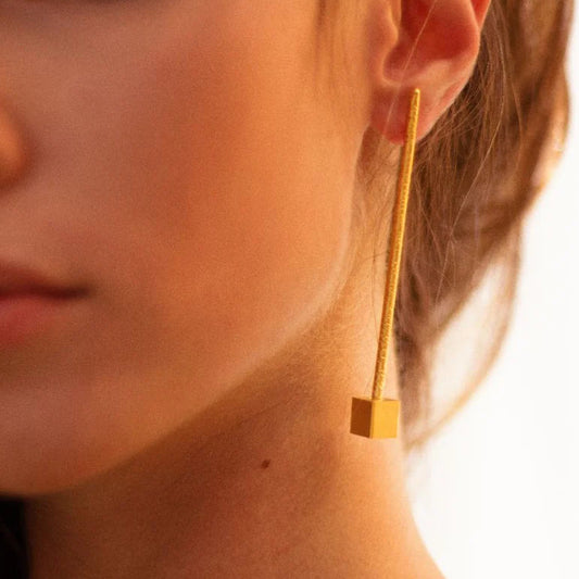 Close-up of a gold earring worn by a person with a blurred background