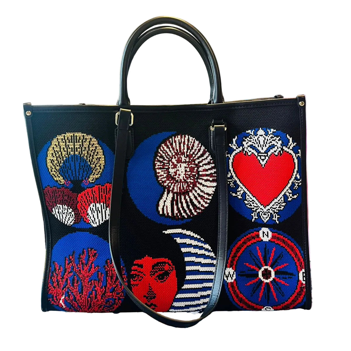 Black handbag with colorful embroidered designs on a glass table.