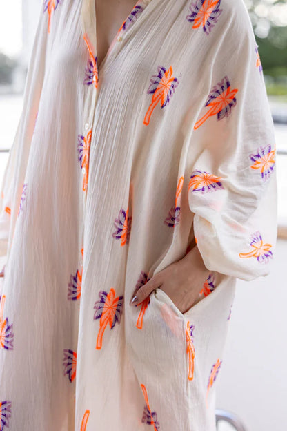 Long bohemian-style shirt dress made from a light and flowy fabric. Its full-length button closure and loose fit create a relaxed yet elegant silhouette.
Decorated with colorful embroidered patterns, it can be worn closed as a dress or open as a layering piece for different styling options