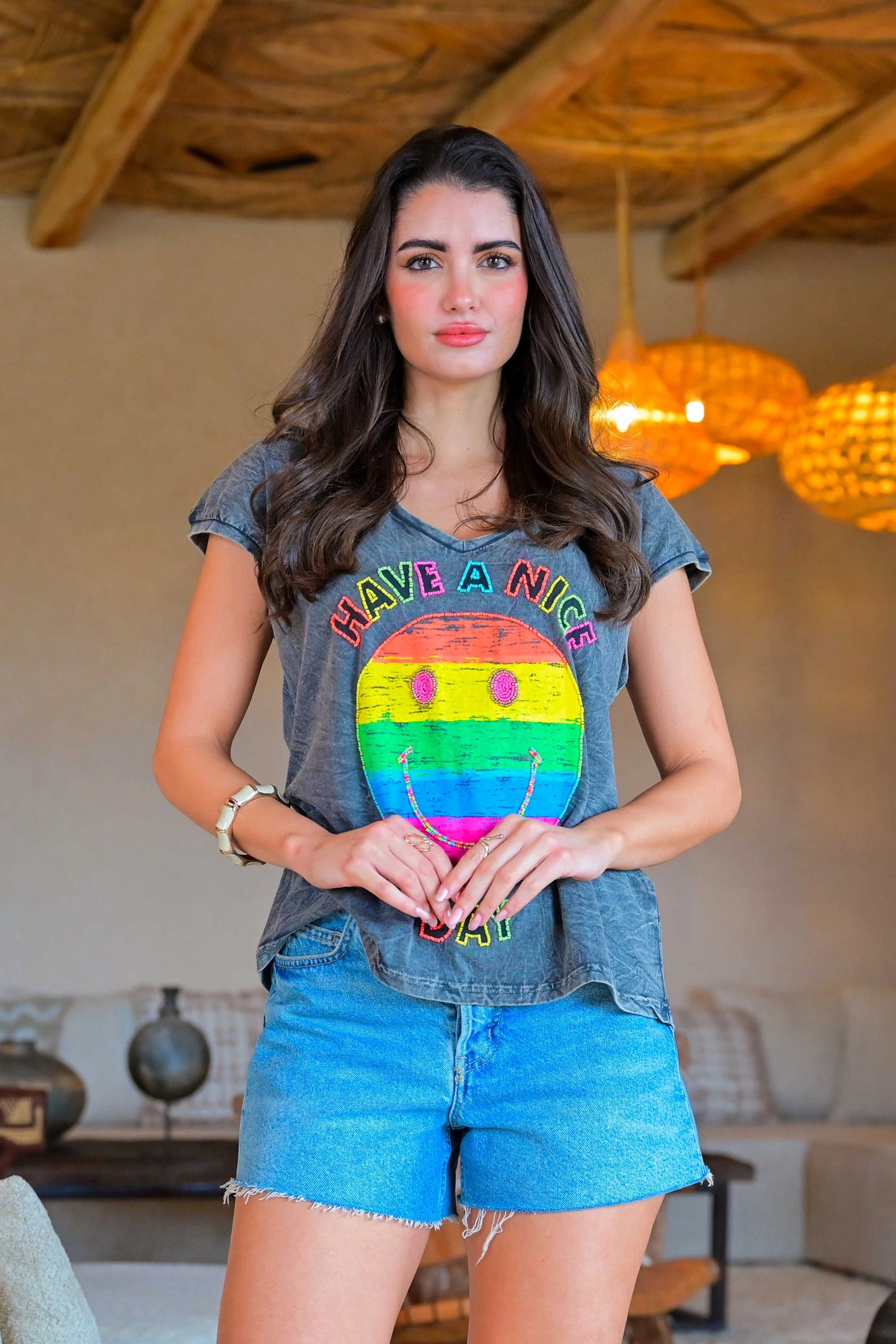 Woman wearing a colorful t-shirt with a rainbow design and text in a casual setting.