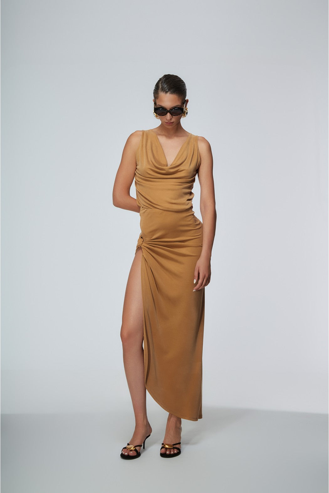 Woman wearing a mustard yellow dress with a slit on a white background