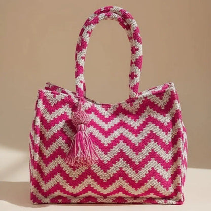 Pink and white zigzag patterned bag with tassel on a beige background