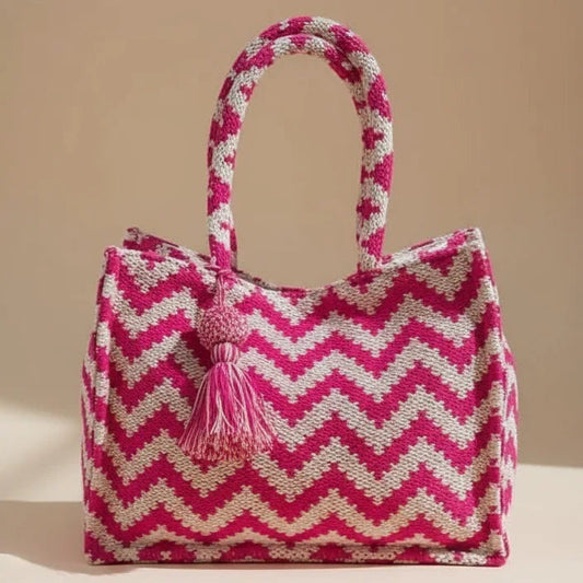 Pink and white zigzag patterned bag with tassel on a beige background