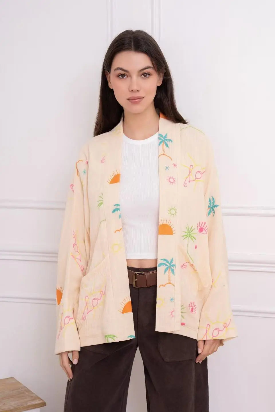 Woman wearing a light-colored cardigan with colorful patterns against a white background